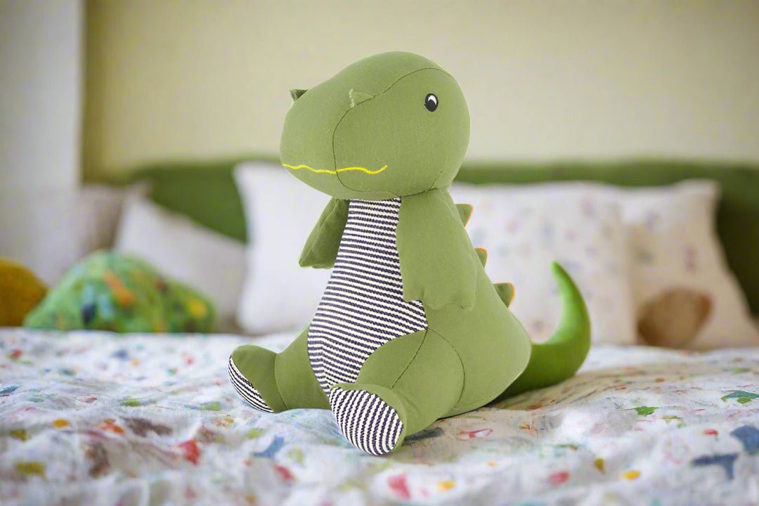 Green dinosaur plush toy with a striped shirt on a white background
