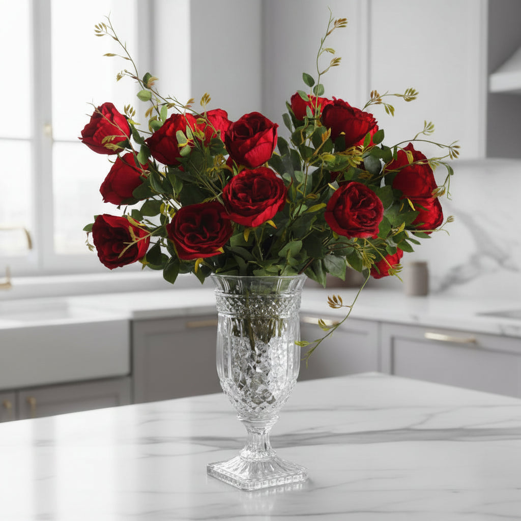 Bouquet of red roses in a clear glass vase on a gray surface with a gray background